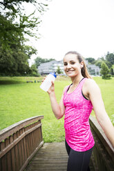 Sportive young woman holding drinking bottle - REAF000156