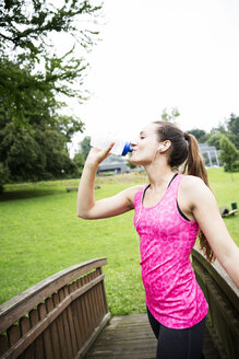 Sportliche junge Frau, die aus einer Flasche trinkt - REAF000157