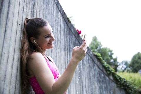 Sportive young woman with smartphone and earbuds stock photo