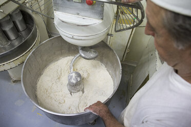 Ein Bäcker beobachtet das Kneten des Brotteigs in einem Industriemischer - ABZF000921