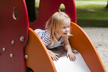 Blondes kleines Mädchen auf der Rutsche eines Spielplatzes - TCF005068