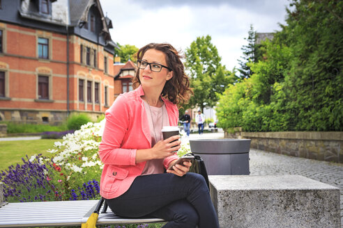 Woman with coffee to go resting on a bench watching something - VTF000544