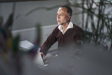 Älterer Mann mit Laptop am Schreibtisch - KNSF000146