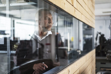 Älterer Mann in einer Fabrik schaut aus dem Fenster - KNSF000151