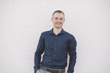 Portrait of smiling businessman in front of white wall - SKCF000145