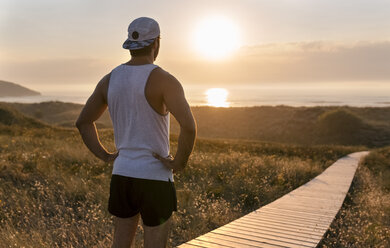 Spanien, Avilés, Sportler, Mann genießt den Sonnenuntergang am Strand - MGOF002135