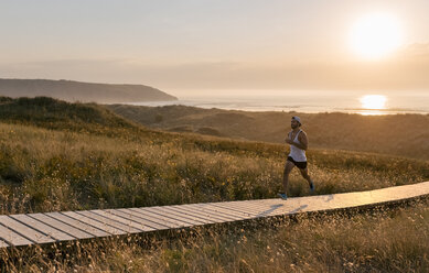 Spain, Aviles, young athlete woman running along a coastal path