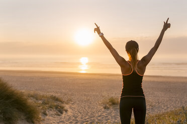 Spanien, Aviles, junge Sportlerin, die den Sonnenuntergang am Strand genießt - MGOF002141