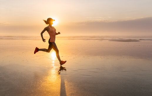 Frau läuft bei Sonnenuntergang am Strand - MGOF002144