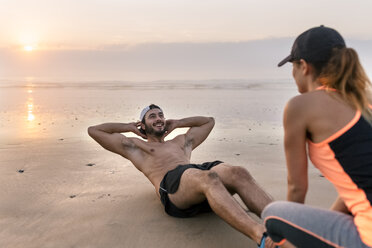 Athletenpaar beim Training am Strand bei Sonnenuntergang - MGOF002150