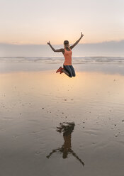 Young athlete woman jumping on the beach in the evening - MGOF002158