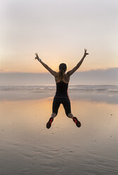 Young athlete woman jumping on the beach at sunset - MGOF002159