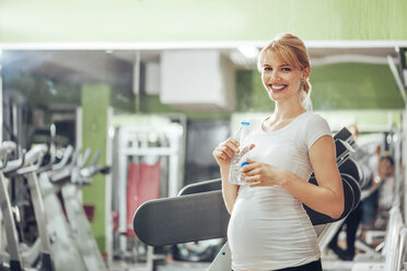 Schwangere Frau trinkt Wasser im Fitnessstudio - ZEDF000258