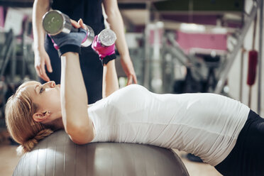 Schwangere Frau macht Übungen mit Handgriffen auf einem Fitnessball im Fitnessstudio - ZEDF000264