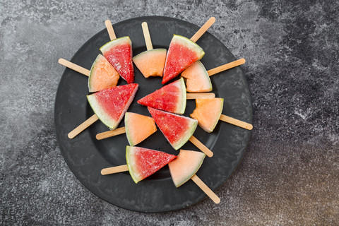 Teller mit Wassermelonen- und Steinmelonen-Eis am Stiel, lizenzfreies Stockfoto