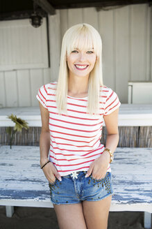 Porträt einer lächelnden blonden Frau mit gestreiftem T-Shirt und Hot Pants - GDF001085