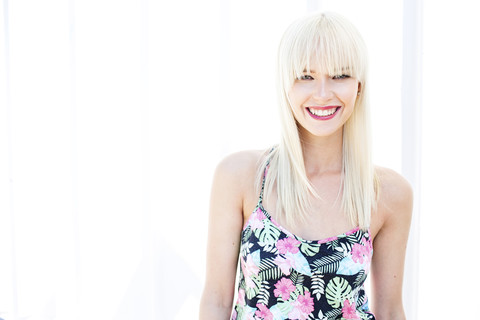 Porträt einer lächelnden blonden Frau vor einem hellen Hintergrund, lizenzfreies Stockfoto