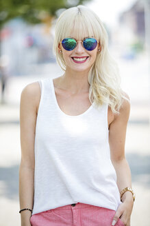 Porträt einer lächelnden blonden Frau mit verspiegelter Sonnenbrille - GDF001100
