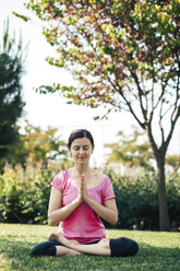 Young woman doing yoga and meditation, outside, eyes closed - BZF000324