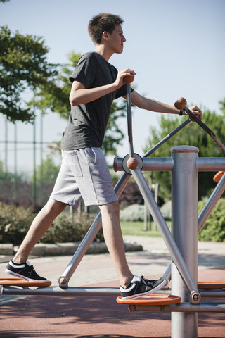 Teenager beim Training an einem Outdoor-Fitnessgerät, lizenzfreies Stockfoto