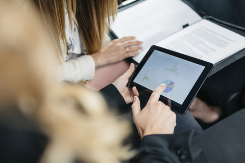 Zwei Geschäftsfrauen mit digitalem Tablet und Dokumenten bei der Arbeit im Auto, lizenzfreies Stockfoto