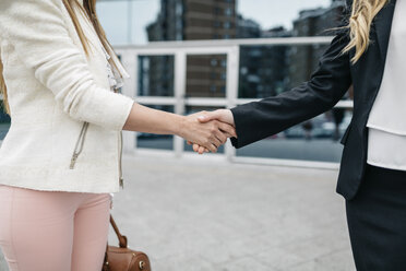 Two businesswomen outdoors shaking hands - DAPF000222