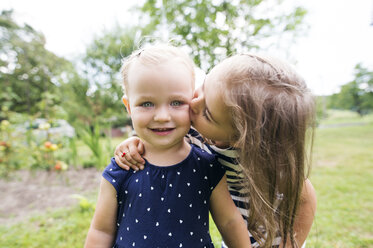 Mädchen küsst ihre kleine Schwester im Garten - HAPF000687