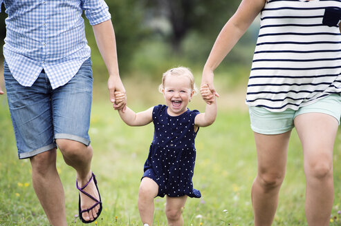 Laughing toddler girl holding hands of parents while running - HAPF000693