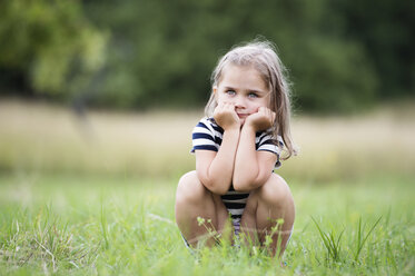 Little girl crouching on a meadow - HAPF000697