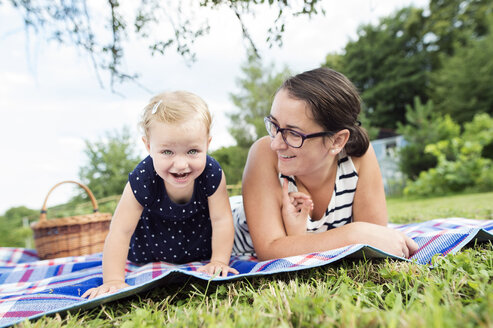 Mother and little daughter together on blanket in a park - HAPF000708