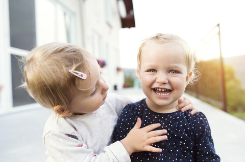 Little girl watching her laughing sister stock photo