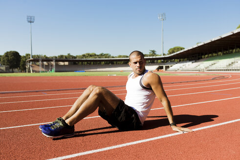 Young sportsman sitting on running track - FMOF000085