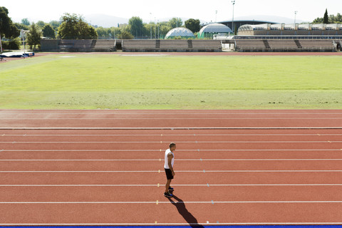 Young sportsman standing on tartan track stock photo