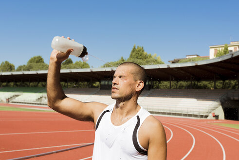 Junger Sportler spritzt sich Wasser ins Gesicht - FMOF000095