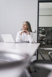 Ältere Geschäftsfrau sitzt am Konferenztisch mit Laptop - KNSF000175