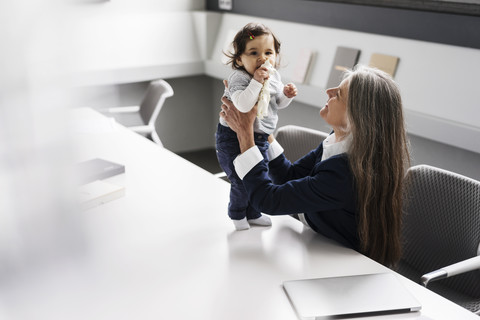 Senior businessswoman in conference room holding baby girl stock photo