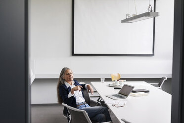 Ältere Geschäftsfrau sitzt am Konferenztisch mit Laptop - KNSF000190