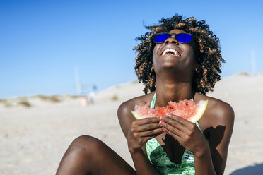 Happy young woman eating watermelon on the beach - KIJF000631