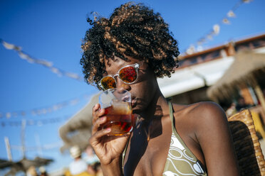 Junge Frau bei einem Drink in einer Strandbar - KIJF000666