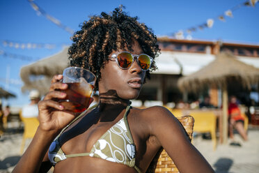 Junge Frau bei einem Drink in einer Strandbar - KIJF000667