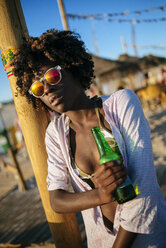 Junge Frau am Strand entspannt mit einer Flasche Bier - KIJF000674