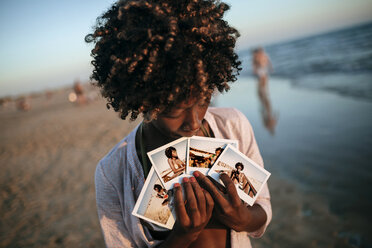 Junge Frau zeigt Sofortbilder am Strand - KIJF000682