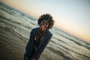 Glückliche junge Frau an der Strandpromenade bei Sonnenuntergang - KIJF000686