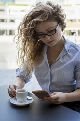 Geschäftsfrau überprüft Handy in einem Café im Freien - MAUF000673