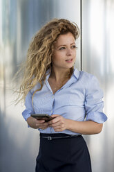 Businesswoman holding cell phone outdoors - MAUF000679