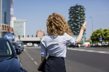 Businesswoman at the roadside hailing a taxi - MAUF000714