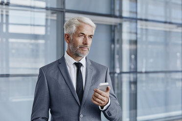 Confident businessman holding cell phone - RORF000237