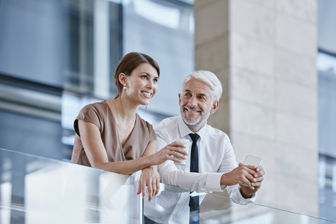 Geschäftsmann und Frau mit Kaffee und Mobiltelefon, lizenzfreies Stockfoto