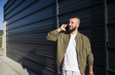 Lächelnder Mann, der mit einem Mobiltelefon telefoniert - RAEF001345