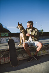 Skateboarder mit seinem Hund in einem Skatepark - RAEF001347